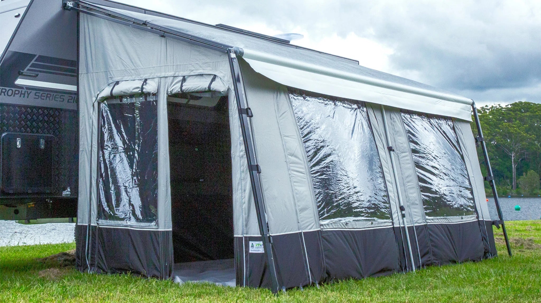 A camper trailer on grass, equipped with a tent and an annexe for enhanced living space.
